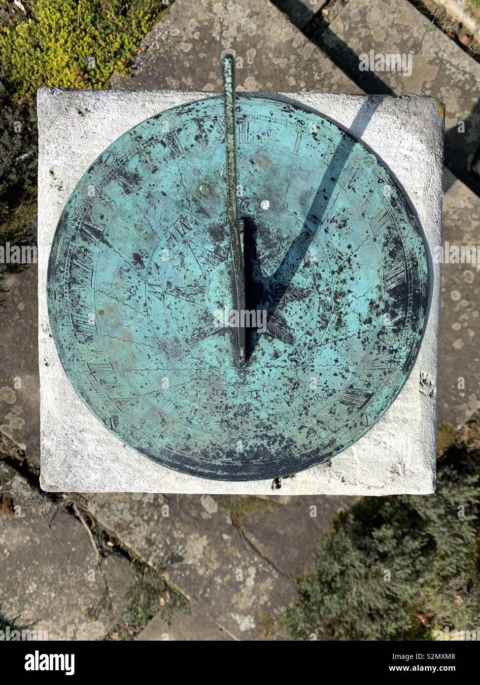 Old sundial showing 2 o’clock, green with verdigris and age - Smartphone Captured Stock Image