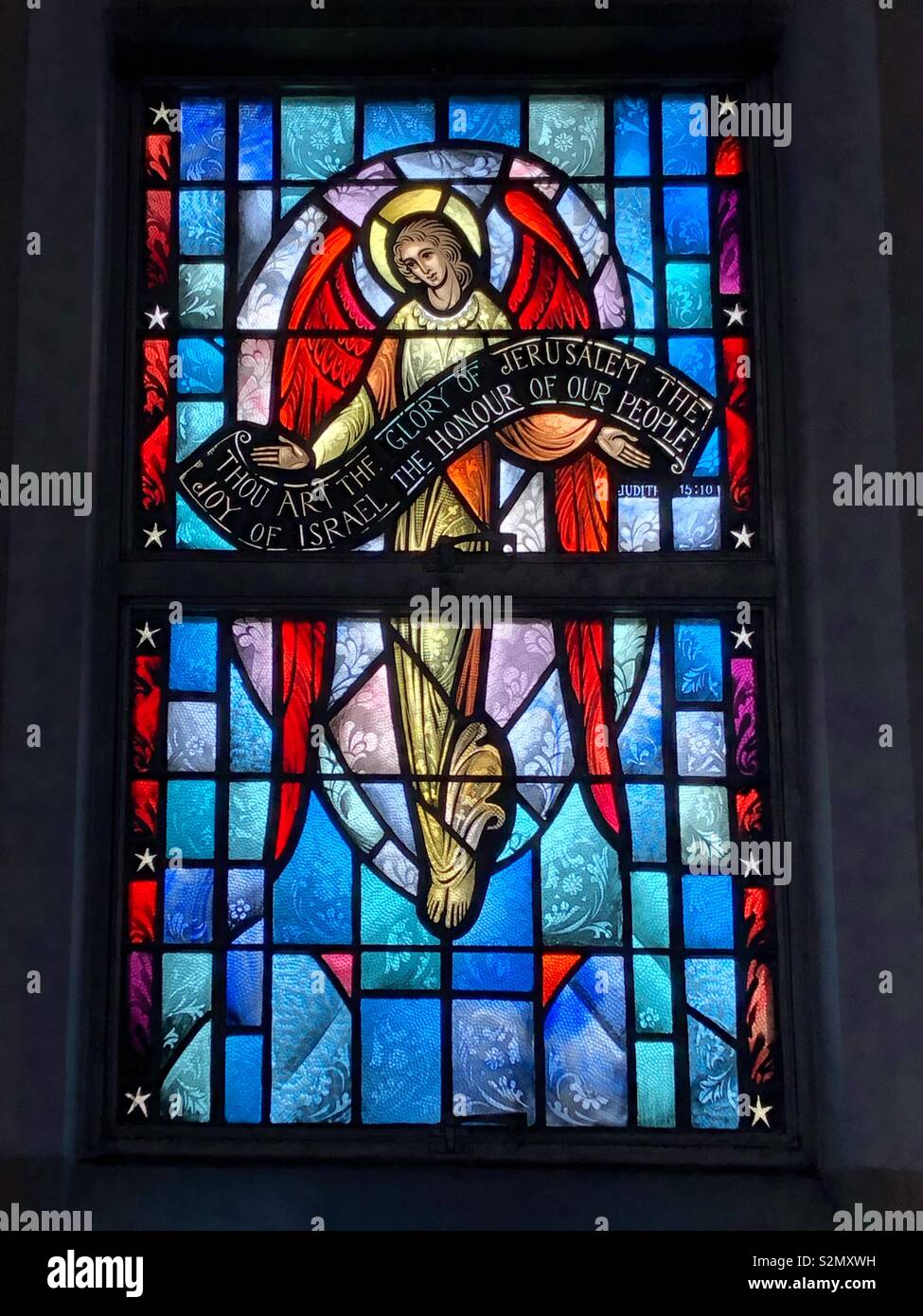 Stained Glass image of angel holding banner honoring Jesus. Taken at St