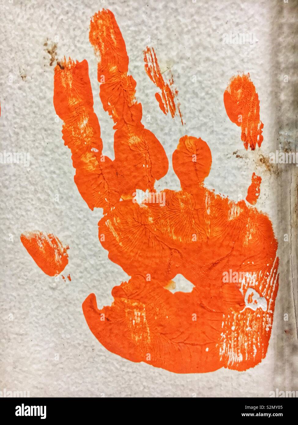 Child’s right hand print in orange paint using hand painting techniques. Stock Photo
