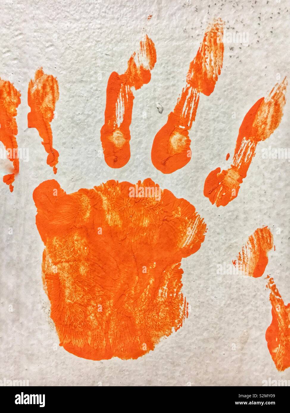 Child’s left hand print in orange paint using hand painting techniques. Stock Photo