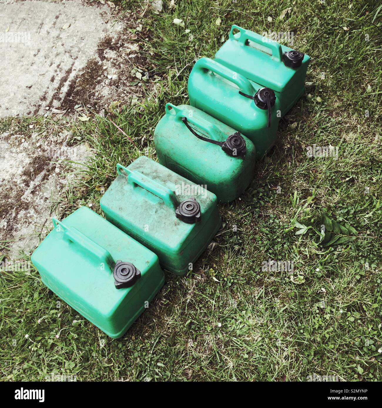 Row of five green petrol cans or Jerry cans, Hampshire, England, United Kingdom. - Smartphone Captured Stock Image