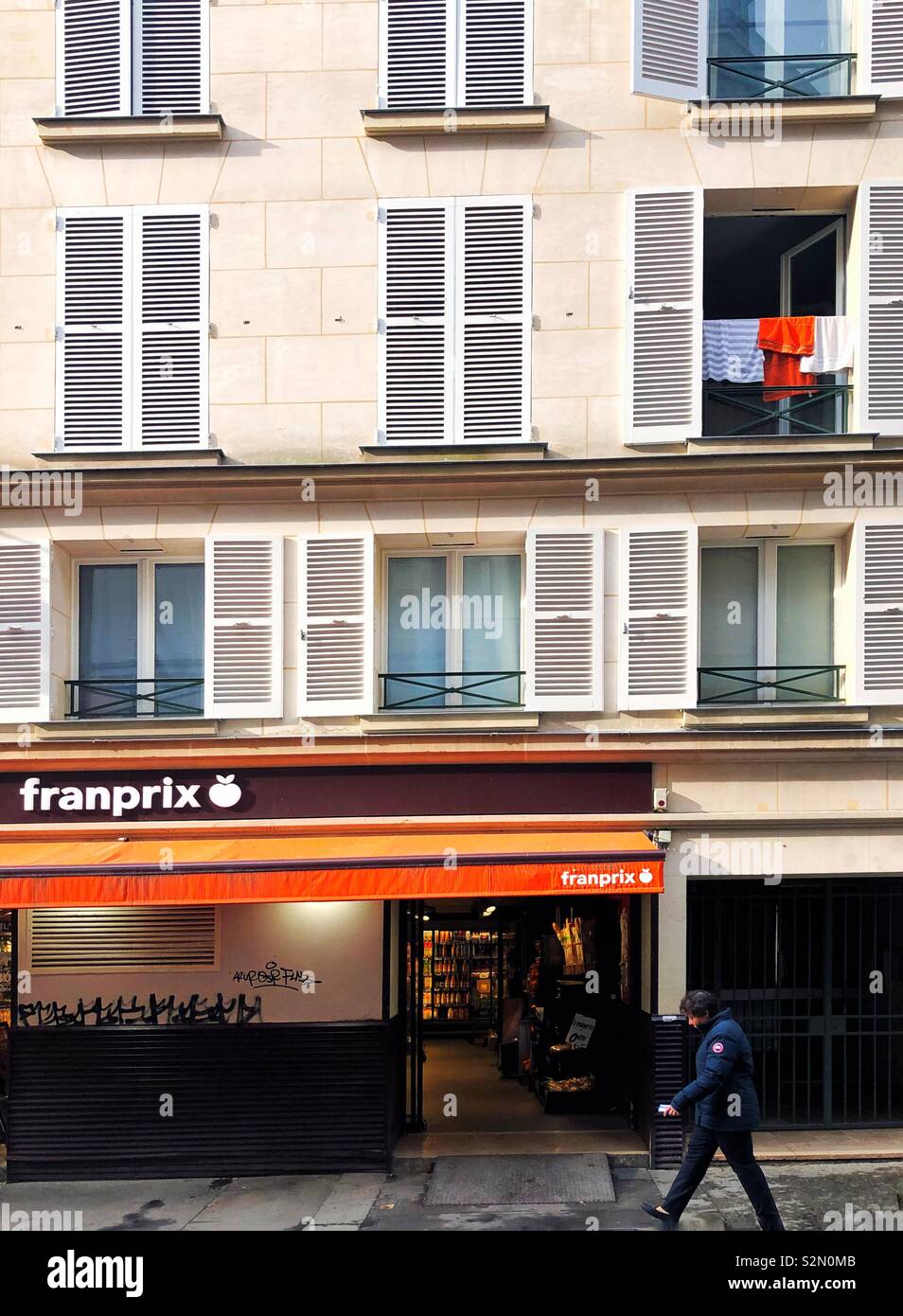Woman walks past grocery chain franprix in paris - Smartphone Captured Stock Image