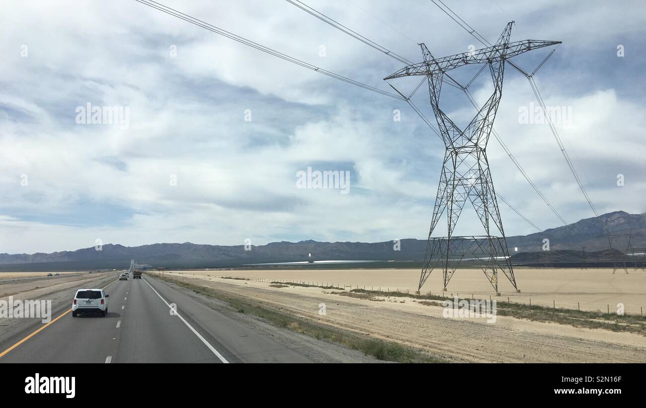 Power pylons bearing high tension electricity cables crossing Interstate 15 near massive solar power generators. Mojave Desert, California. - Smartphone Captured Stock Image