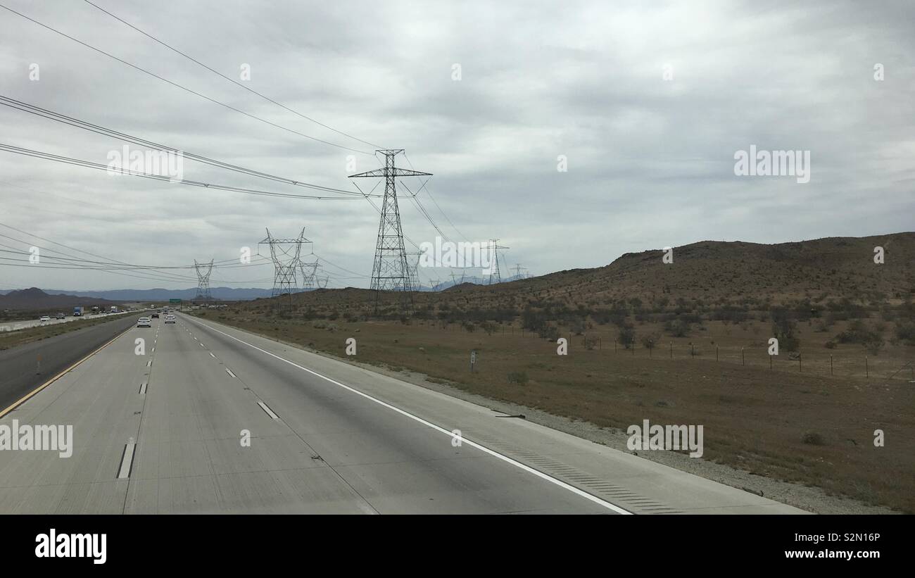 Freeway with power pylons and high Voltage electric cables crossing in mountainous, Apple Valley region of California. Overcast day - Smartphone Captured Stock Image