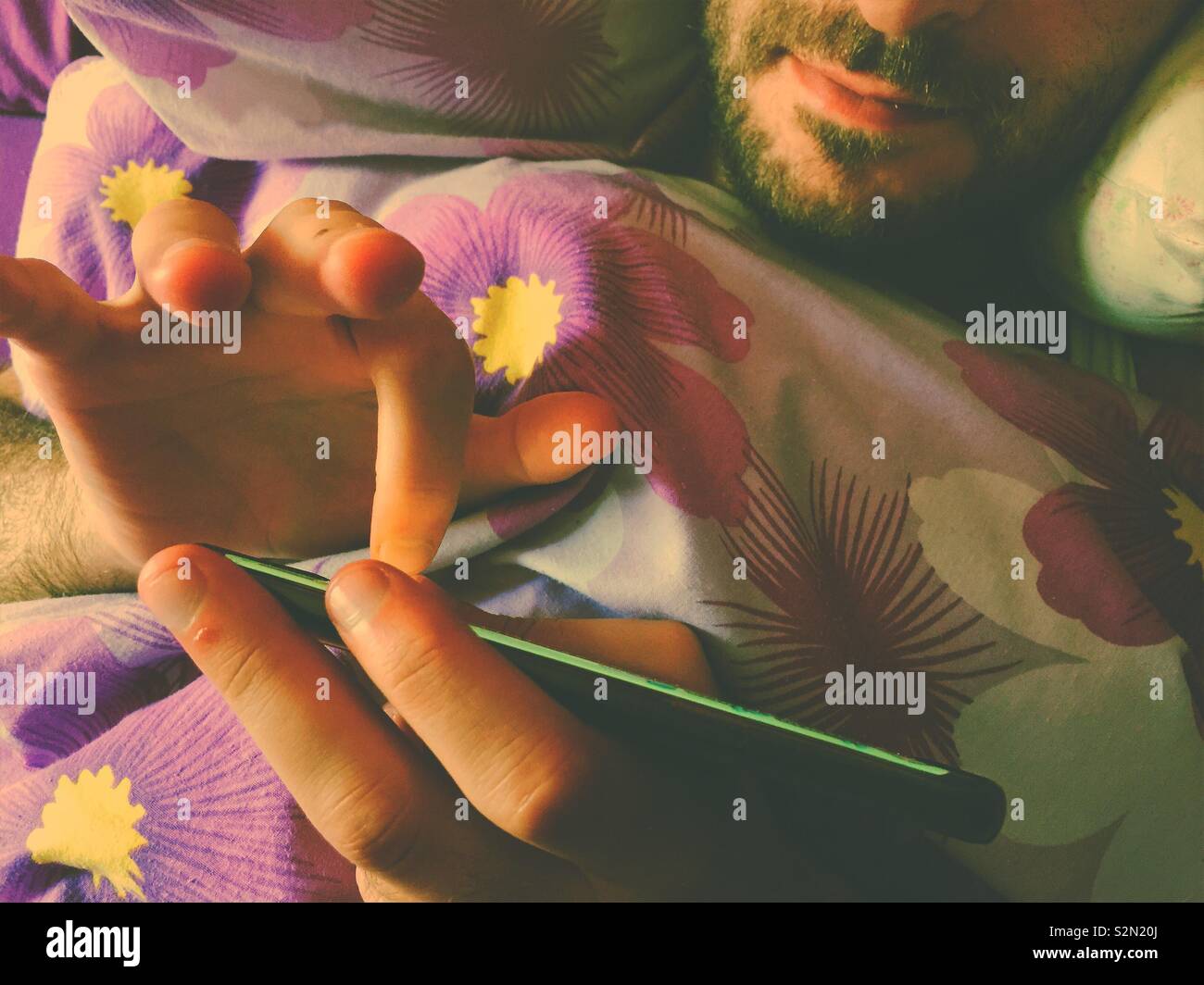 Man using smart phone in bed - Smartphone Captured Stock Image