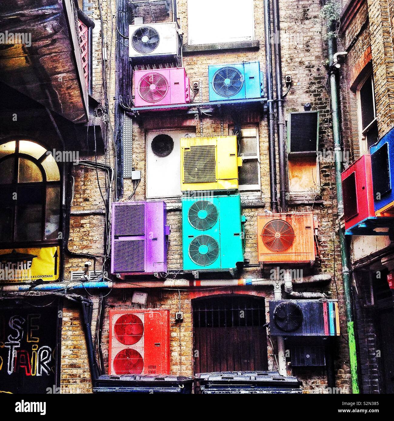 Multi coloured air conditioning units on the rear of a building in