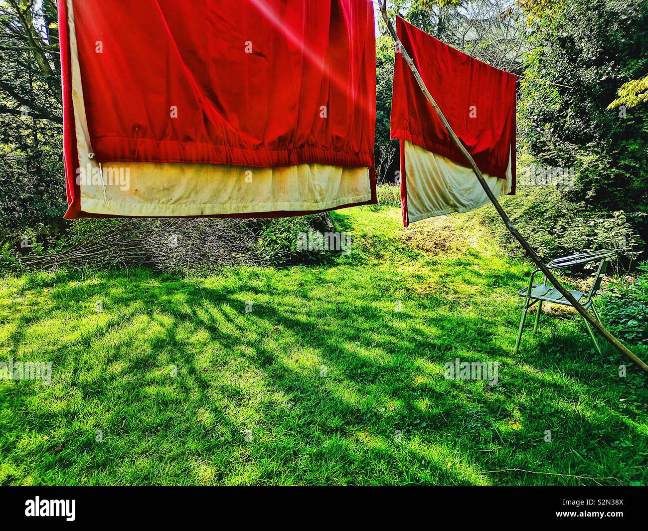 Red curtains hanging in garden to freshen, spring cleaning Stock Photo
