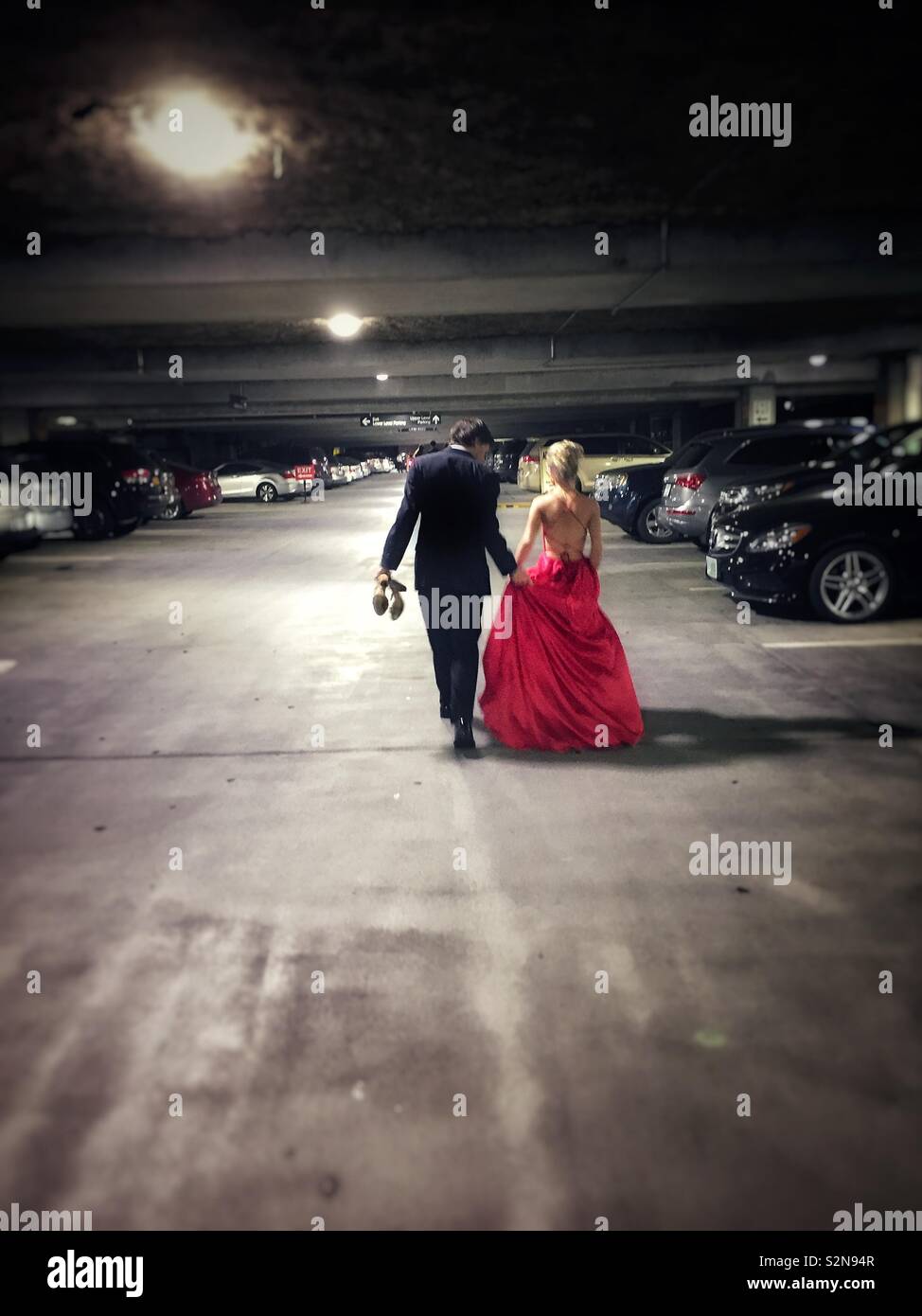 Prom couple going back to their car in a parking garage at the end of the night - Smartphone Captured Stock Image
