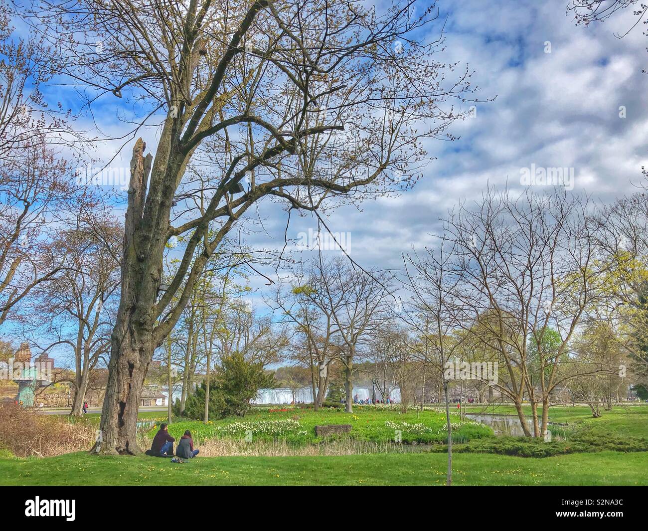 A couple sitting on the grass enjoying a beautiful spring day in Niagara Falls, Canada. - Smartphone Captured Stock Image