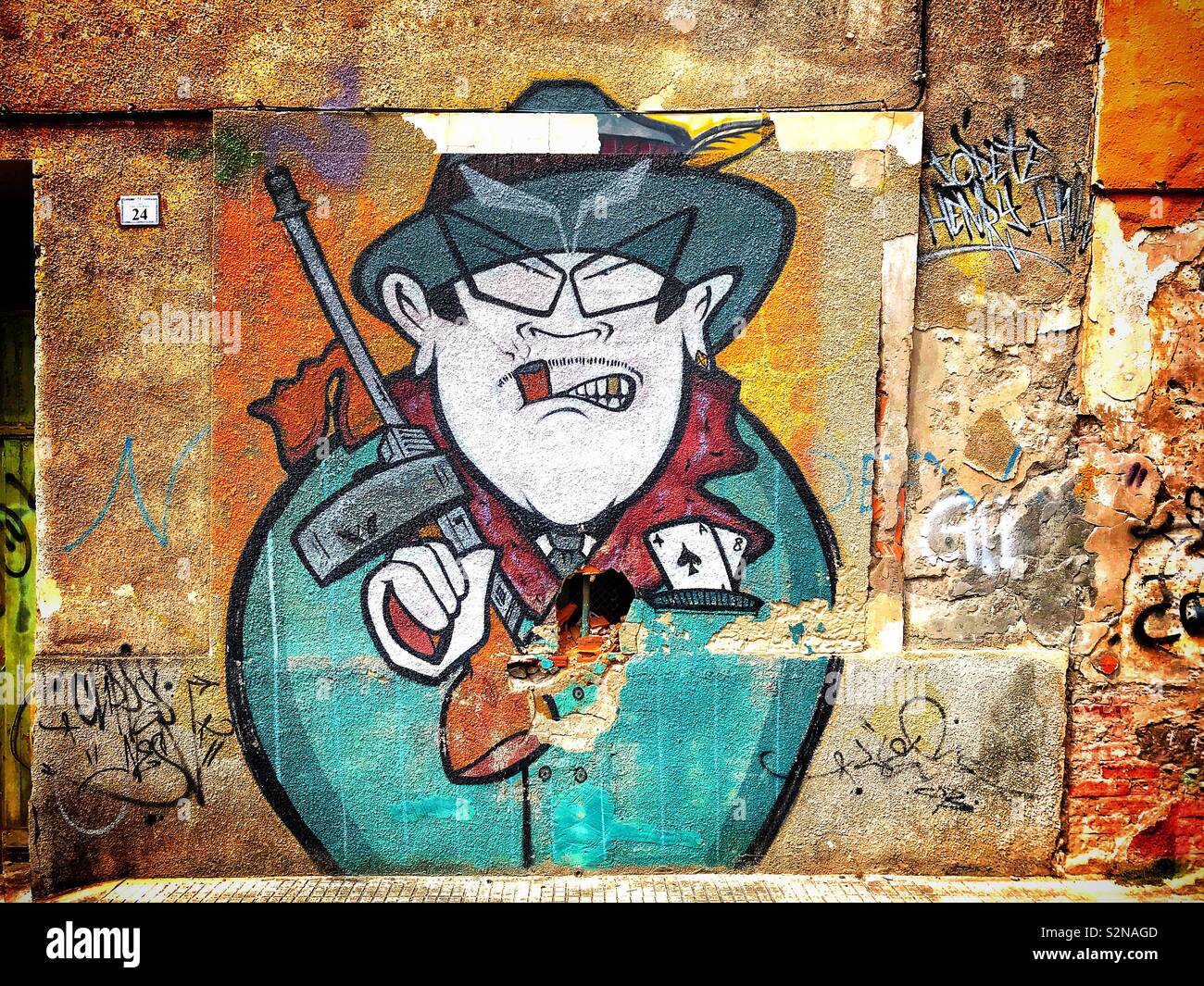 Mural art depicting a cartoon gangster character holding a machine gun, painted on the wall of derelict building in the Spanish fishing village of Santoña Stock Photo