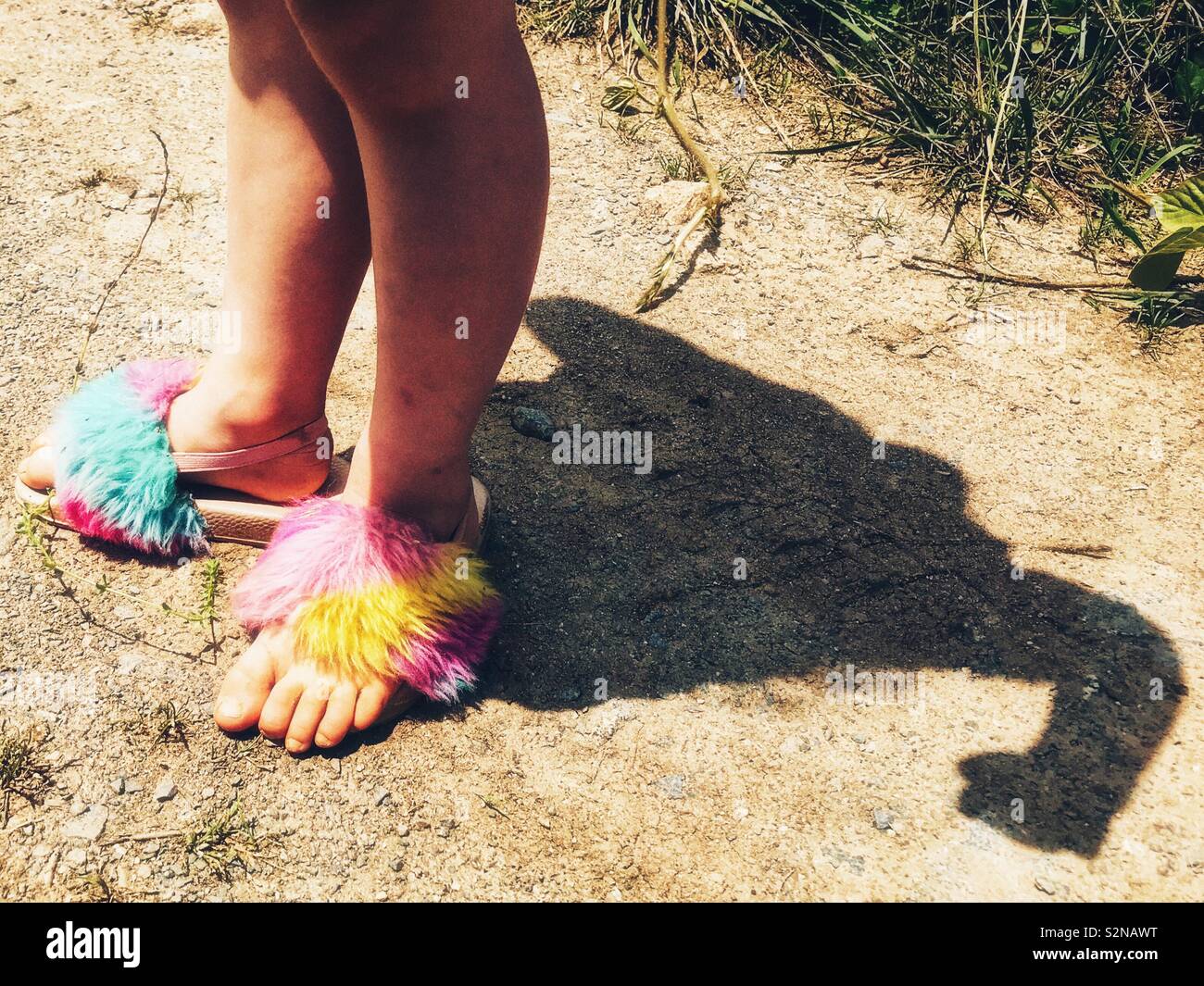 Fuzzy colorful sandals on the feet of a small girl in summertime photo