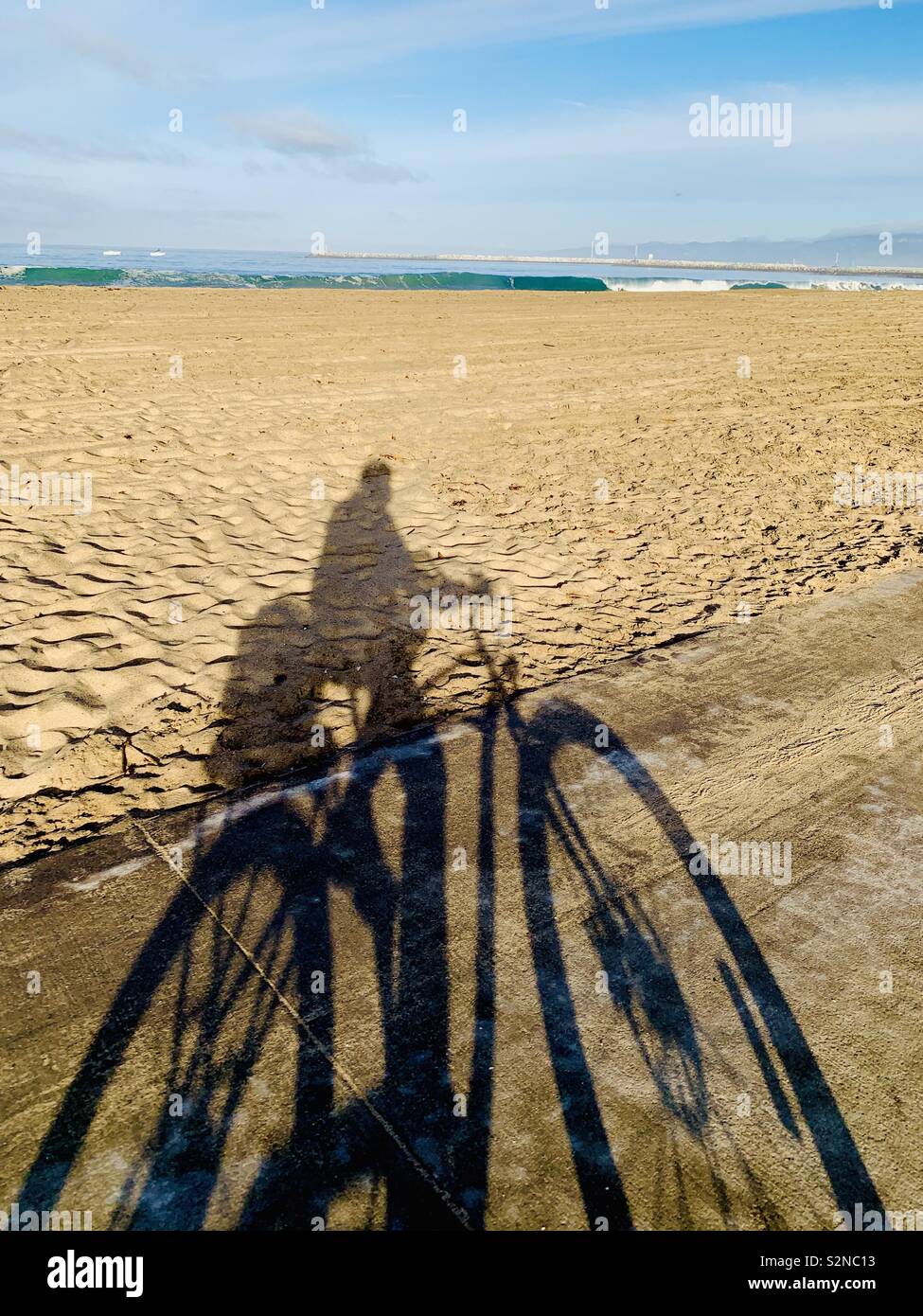 Shadow of a person riding their bike alone the beach. Playa Del Rey, California USA. - Smartphone Captured Stock Image