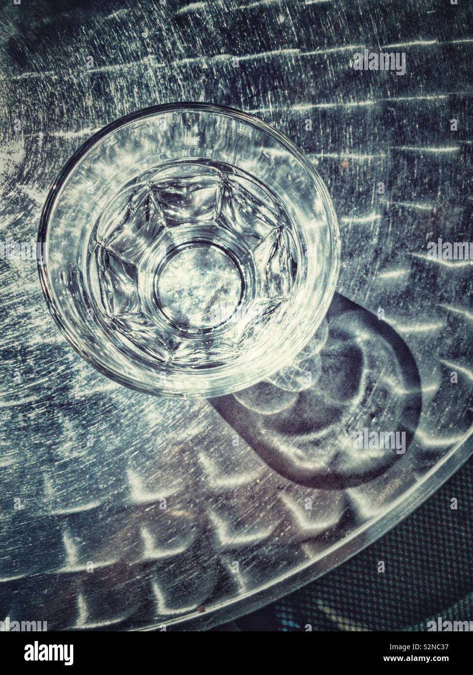 Water in clear glass on metal table, outdoors with hard shadows from bright sunlight. - Smartphone Captured Stock Image