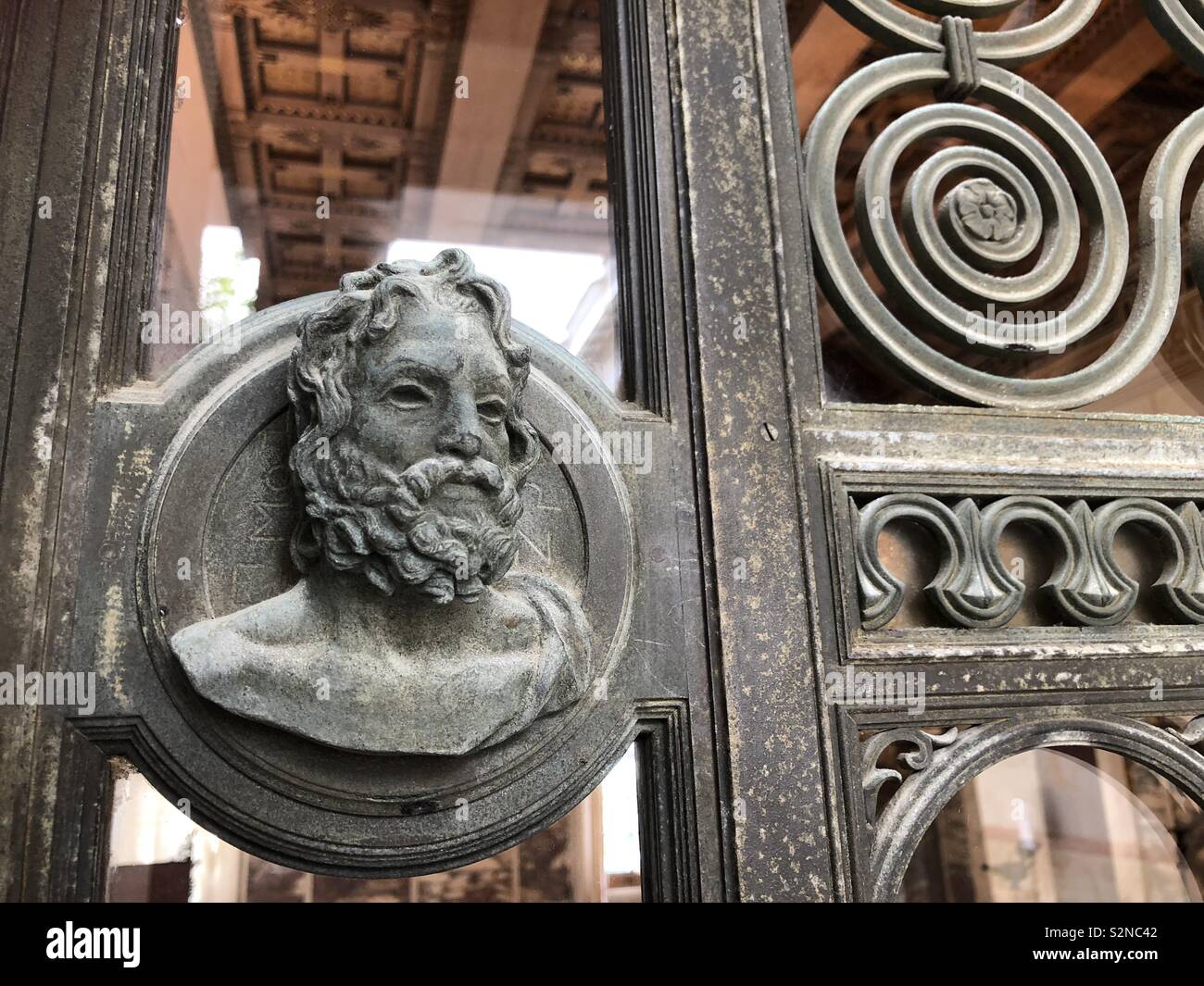 Decorative Bronze decorative casting, part of a door in Villa Kerylos, looking into one of the rooms, featuring a Greek god and spiral and other decorative designs. Stock Photo