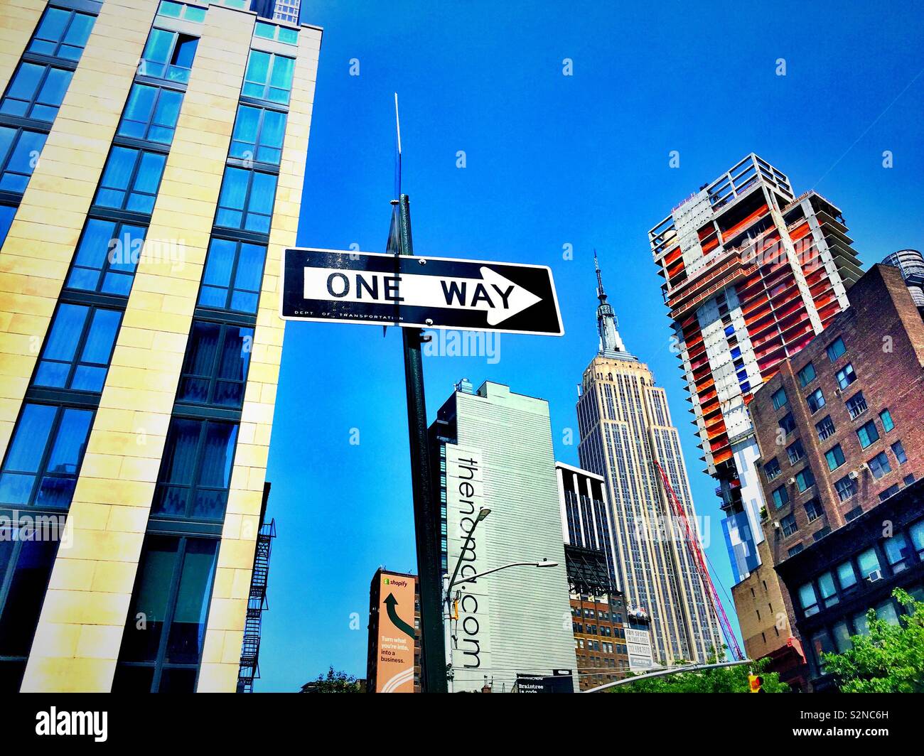 The Empire State building and a high-rise under construction as seen from a one-way street and Chelsea, New York City, United States - Smartphone Captured Stock Image