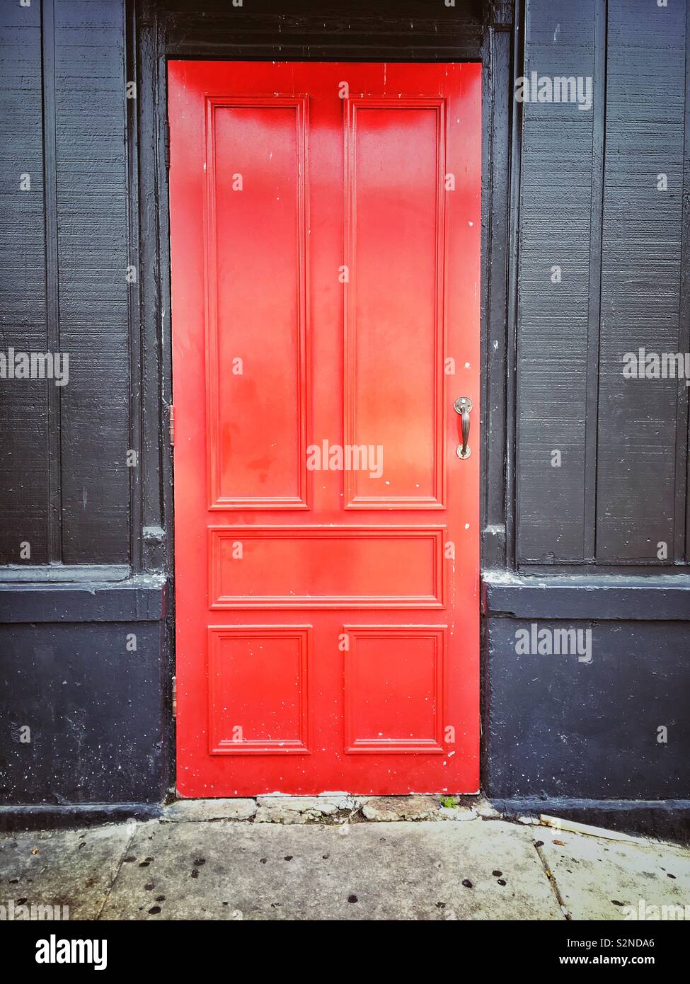 A red door at a black wall - Smartphone Captured Stock Image