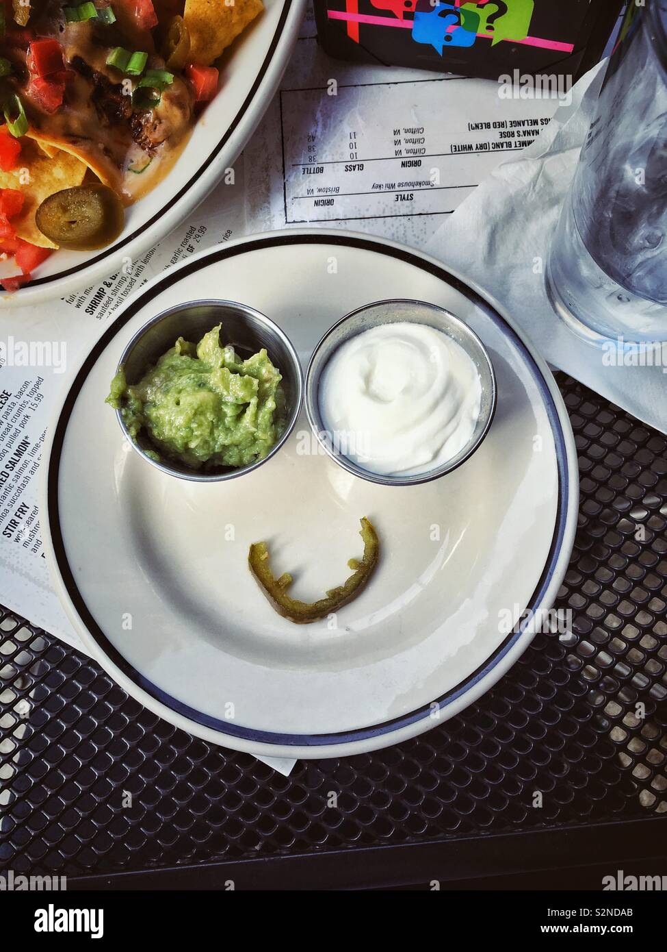 Guacamole and sour cream on a plate with jalapeño. Smiley face emoji. Stock Photo