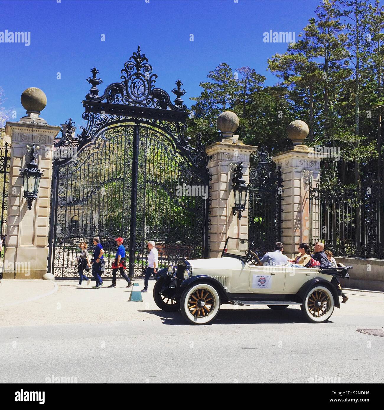 An antique car stops in front of the gate near The Breakers mansion, Newport, Rhode Island, United States - Smartphone Captured Stock Image