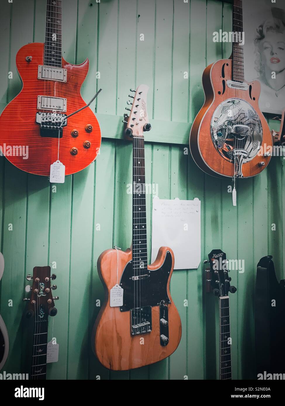 Photo of Marilyn Monroe by display of electric guitars on mint green