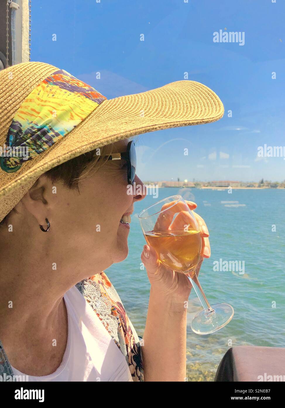 Woman sipping wine by the sea Stock Photo