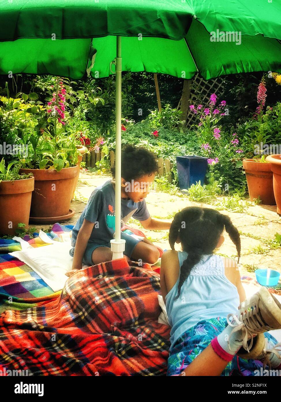 Children play in the garden under an umbrella - Smartphone Captured Stock Image