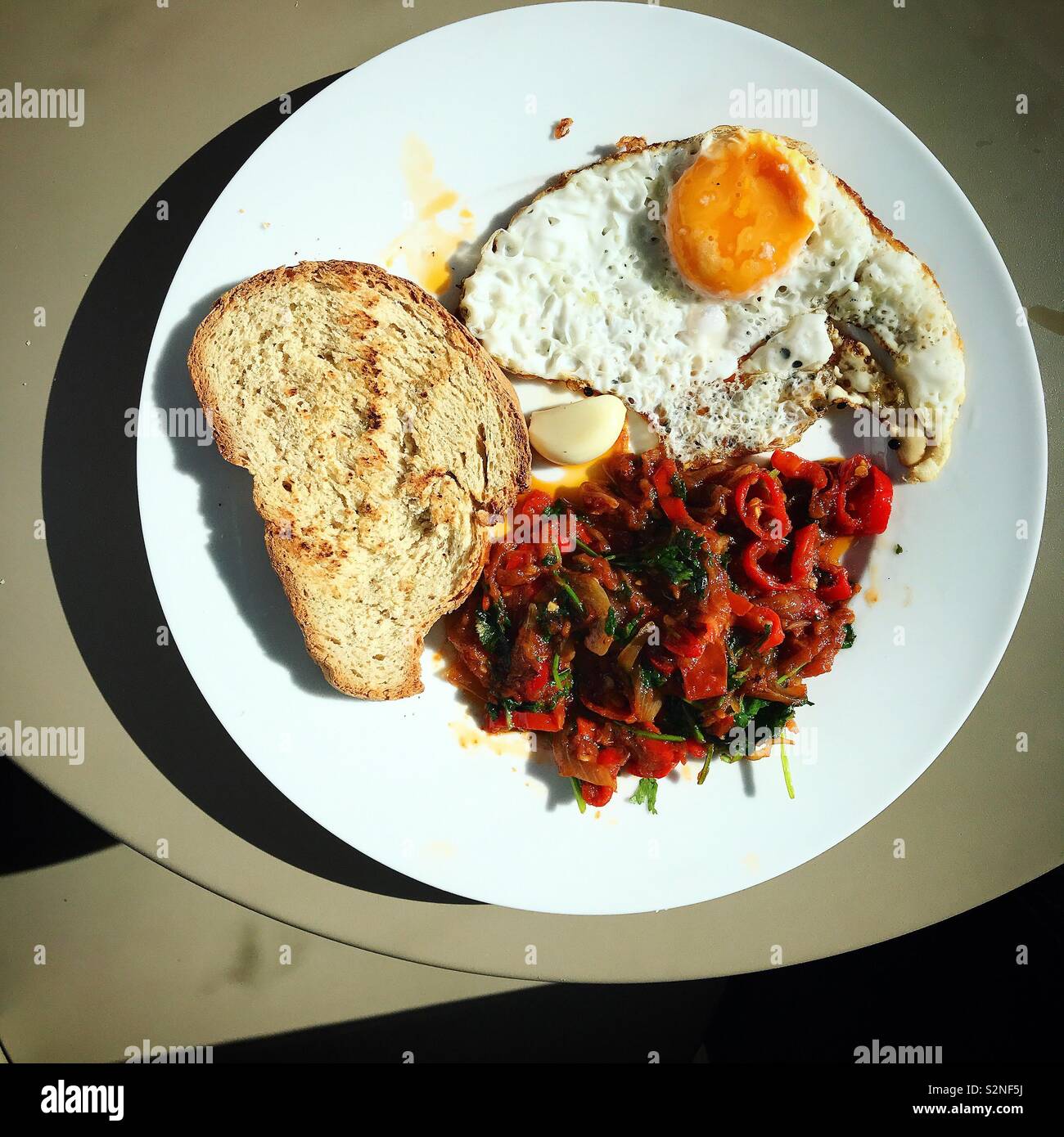 Red sauce, fried eggs and toasted bread in a plate in restaurant in Fatima, Portugal - Smartphone Captured Stock Image