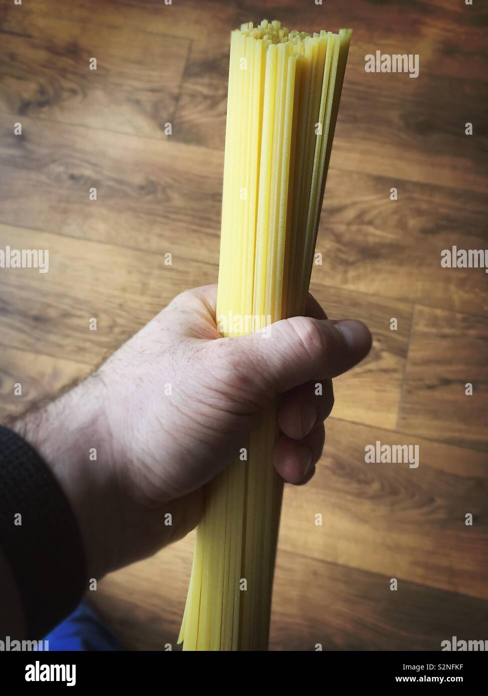 Handful of long spaghetti or linguine pasta ready to drop in boiling water Stock Photo