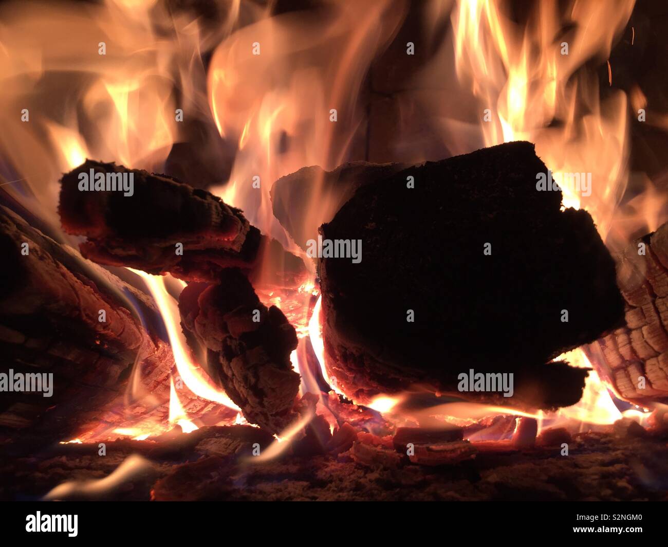 Close-up of wood burning in an outdoor fireplace. - Smartphone Captured Stock Image