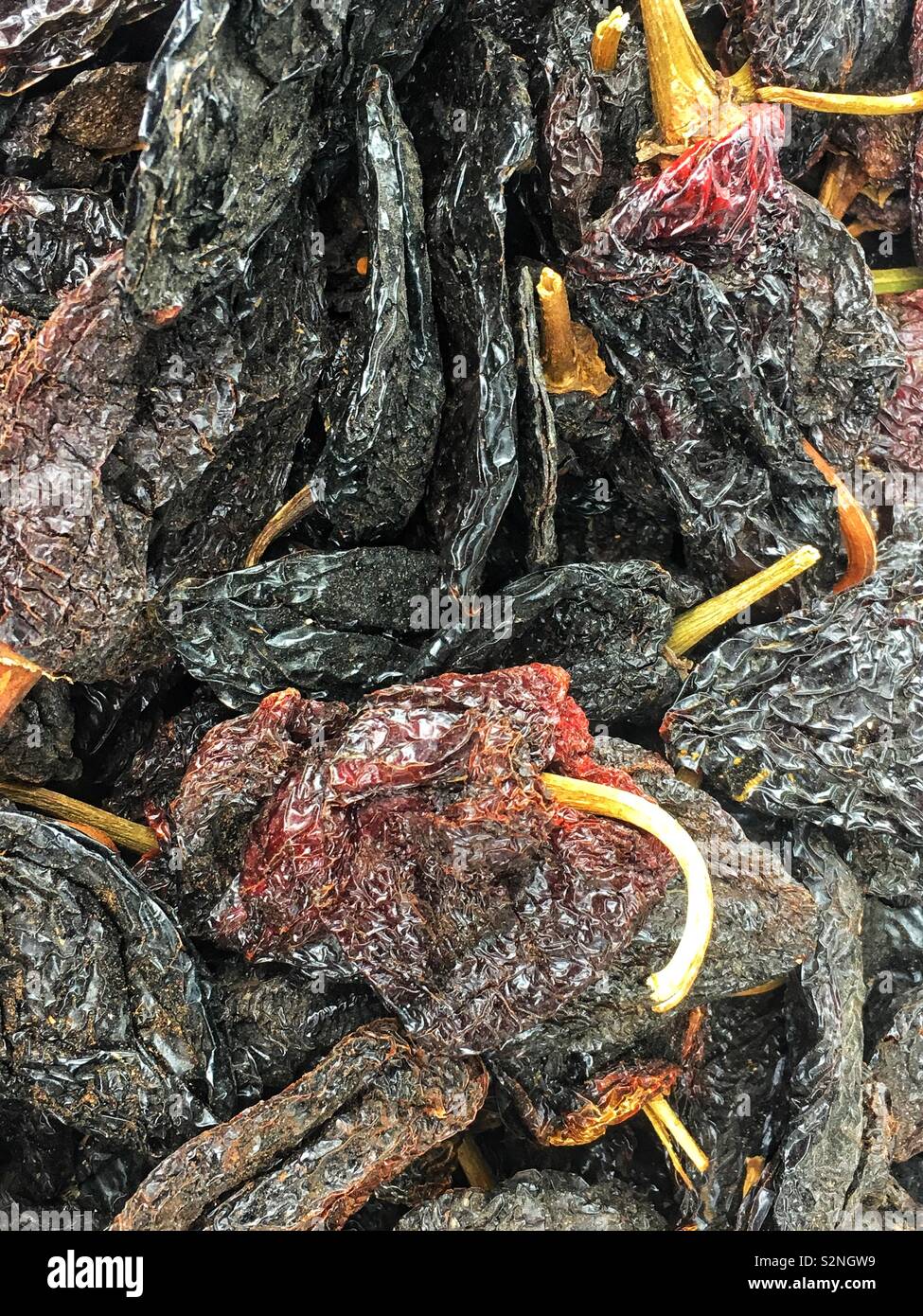 Full frame of dried whole ancho poblano Chile peppers for sale as fresh produce. Stock Photo