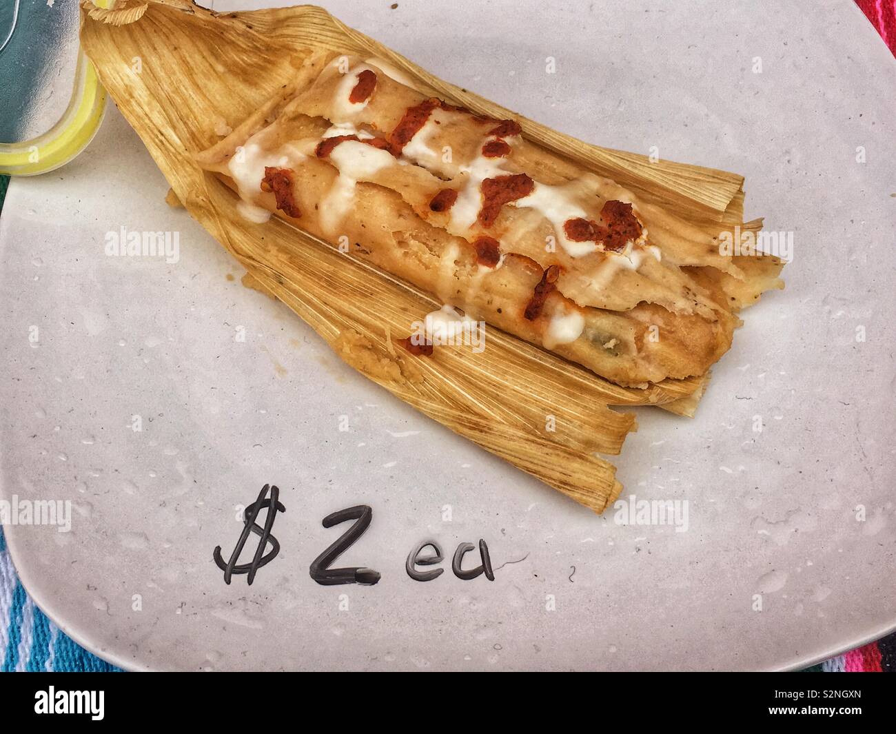 Display plate of one tomale with cheese and delicious mole sauce baked in a corn husk for $2 each. - Smartphone Captured Stock Image