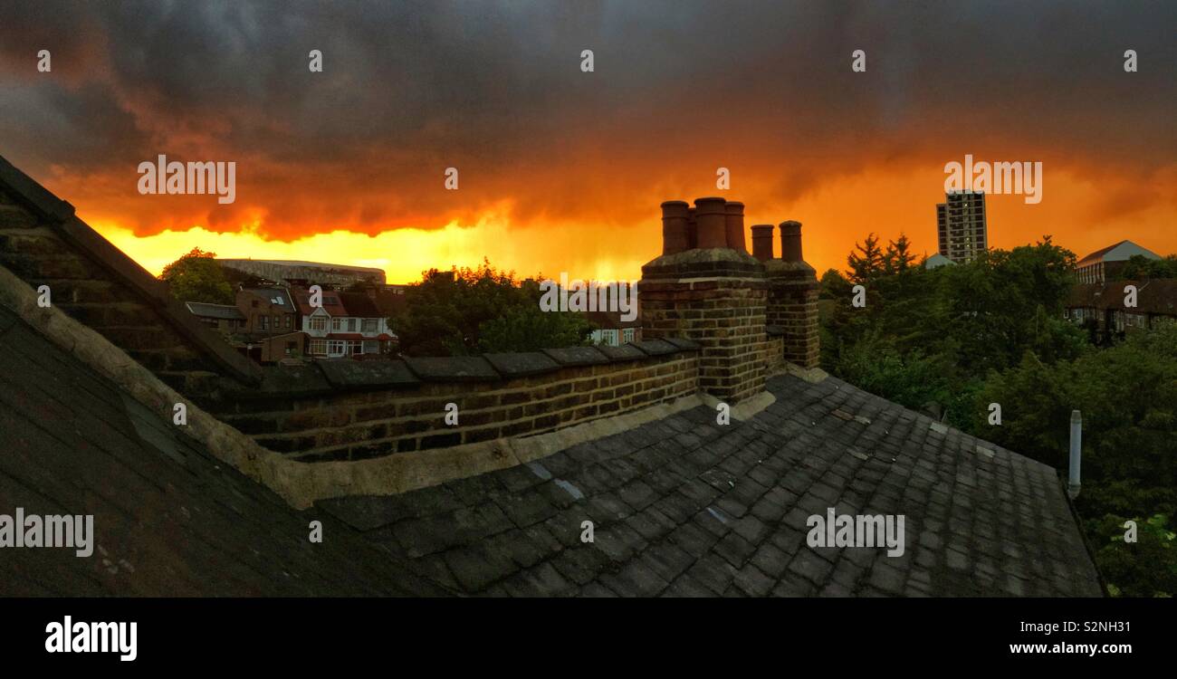 A dramatic and fiery sunset over the rooftops of Tottenham, London. The Spurs football stadium can be seen in the distance, far left. Stock Photo