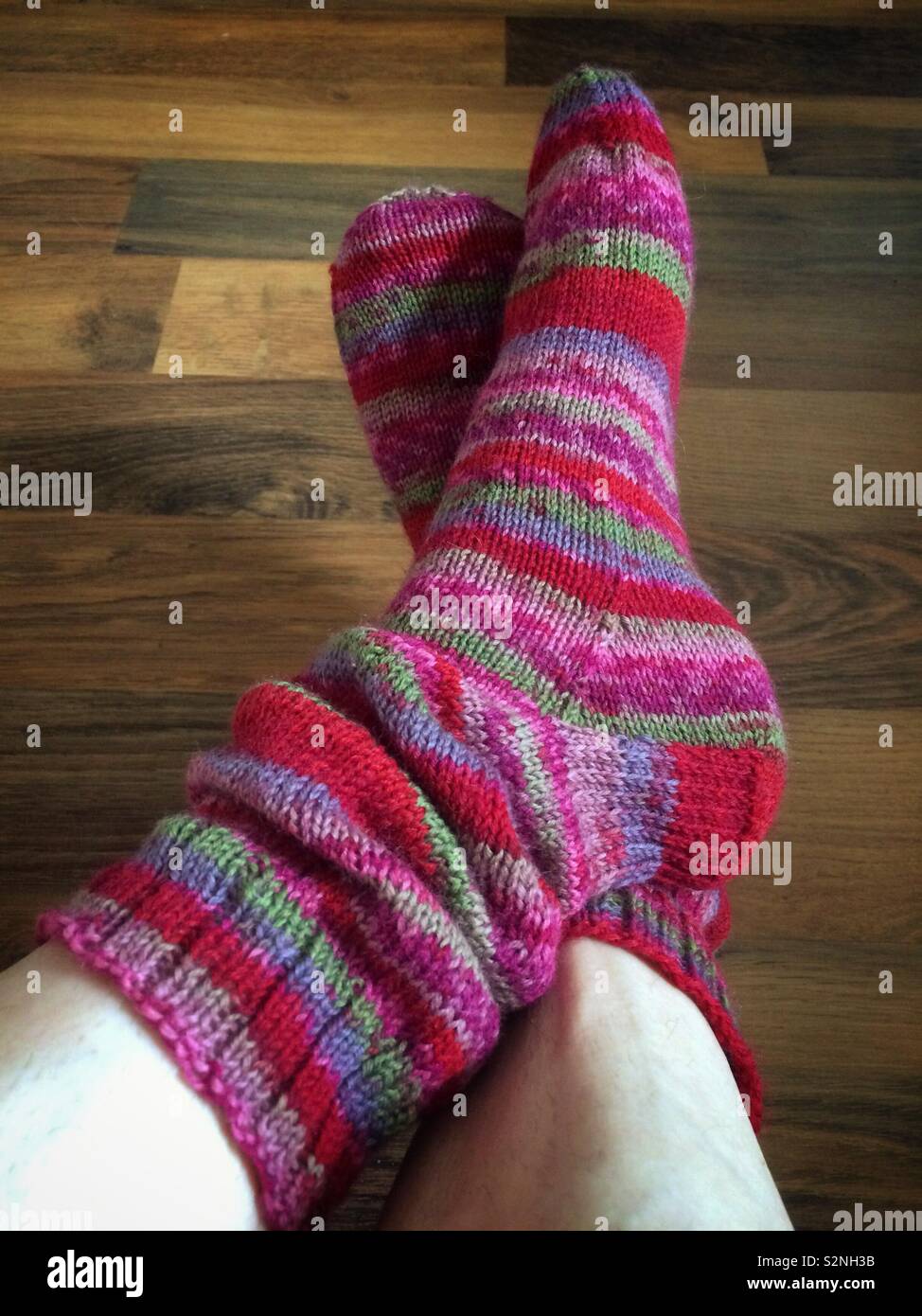Closeup of a woman’s legs and feet, wearing cosy hand knitted slouchy socks. - Smartphone Captured Stock Image