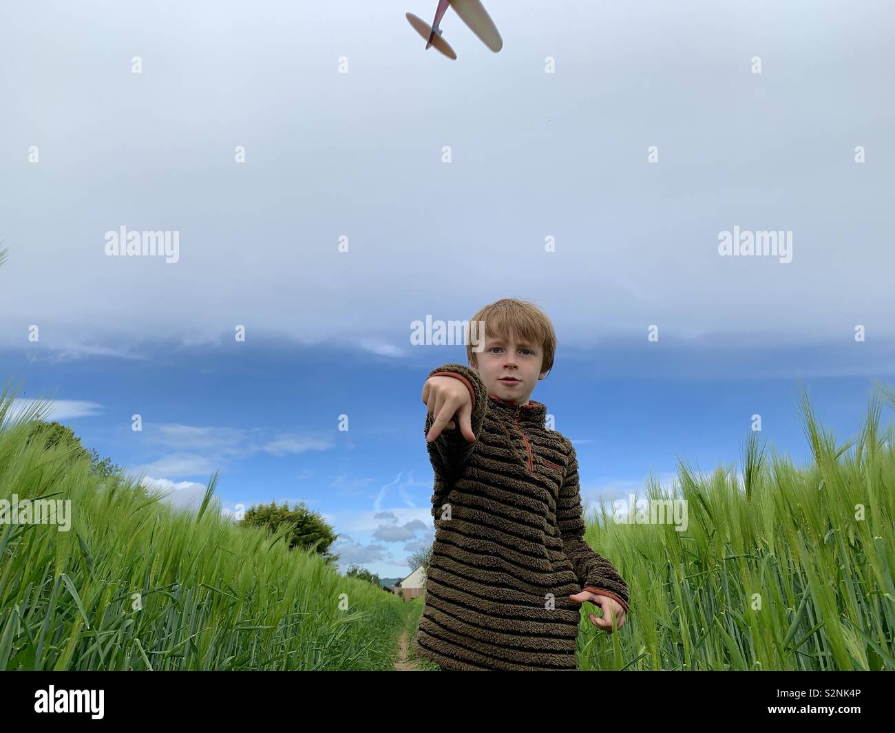 7 year old boy throwing a model plane in a field Stock Photo