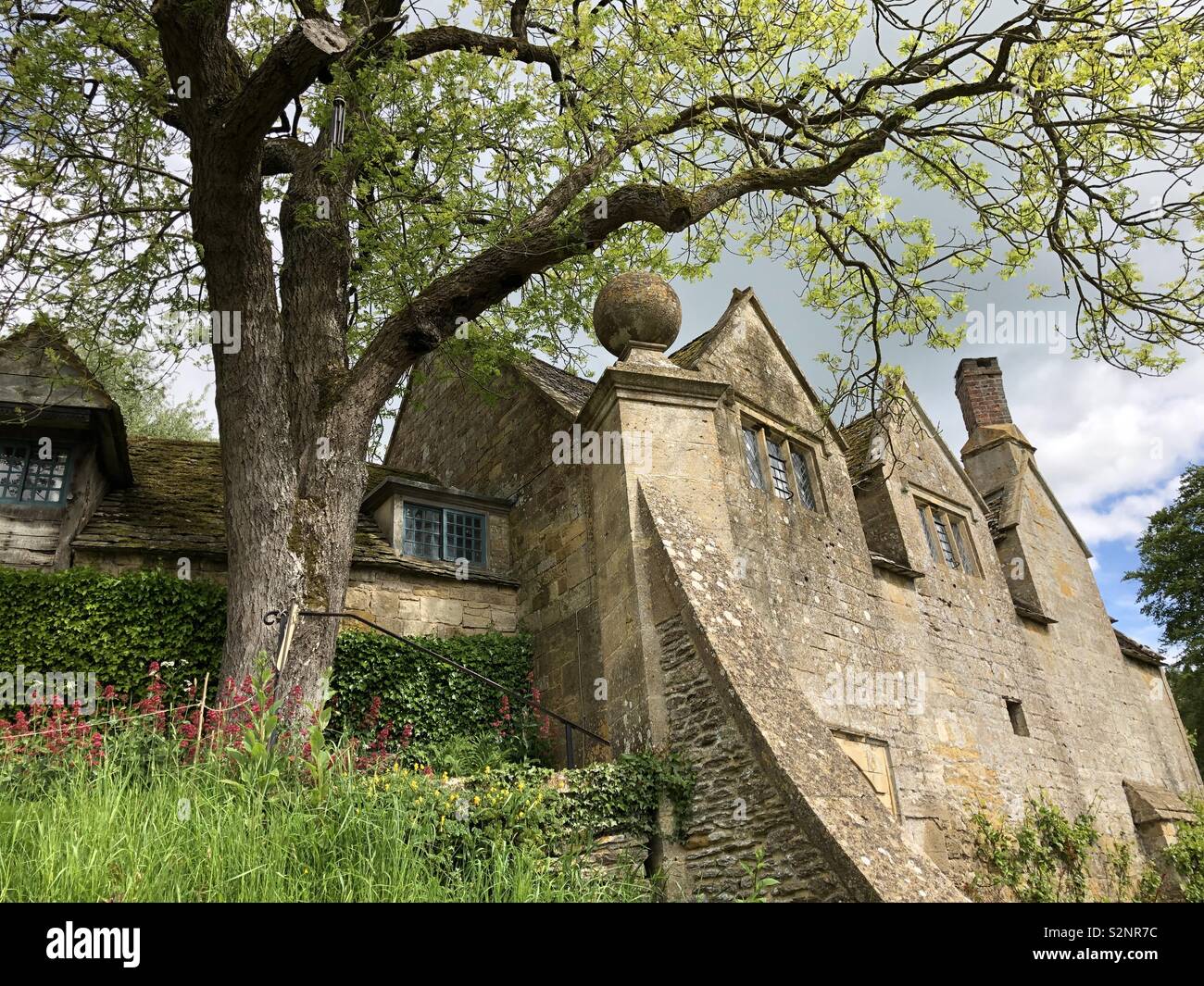 Panorama of the characterful and beautiful rear elevation/ frontage of Snowshill Manor and gardens and bank of wild flowers in the Cotswolds. Stock Photo