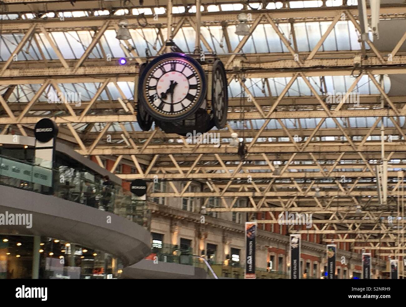 Four-sided clock hanging from the rafters in Waterloo Train Station, London. Stock Photo