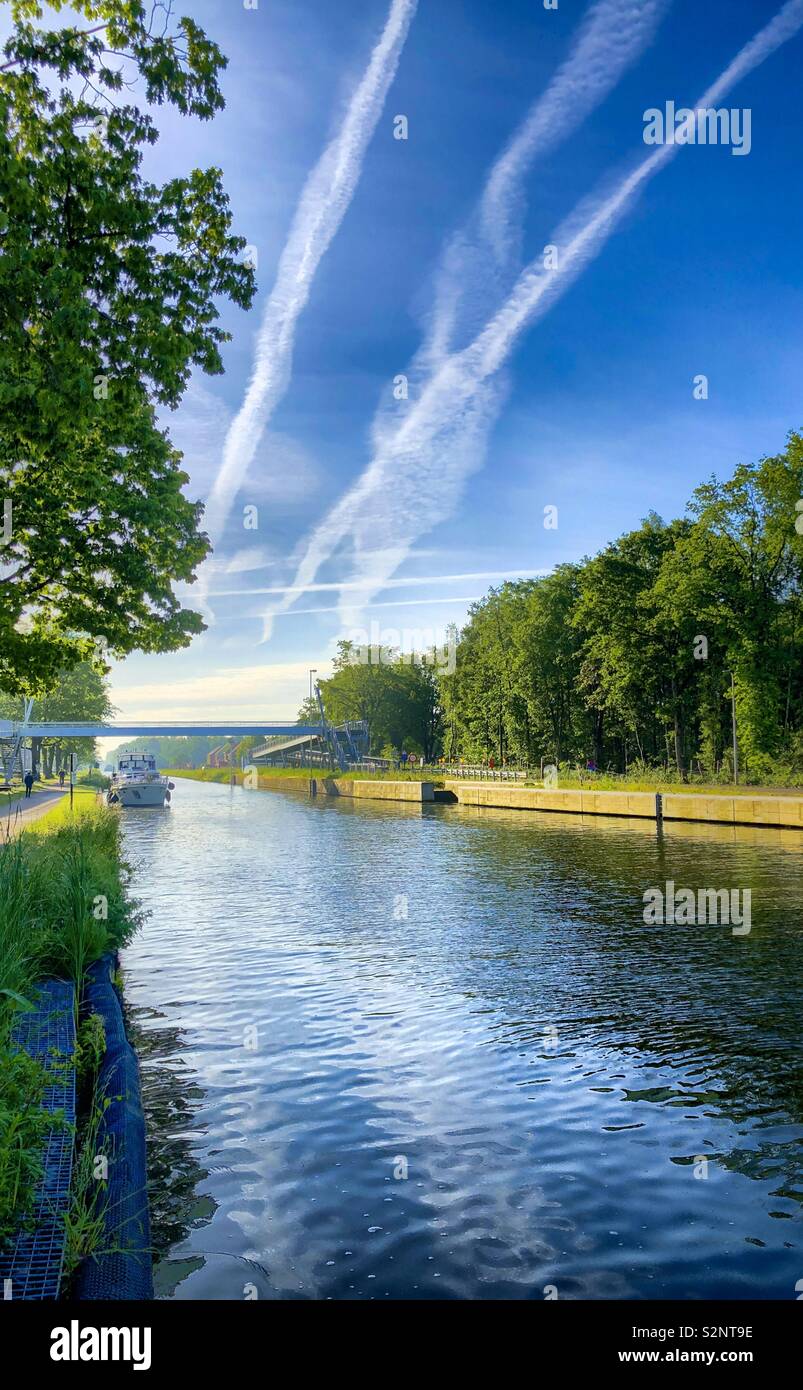 Yacht on a river between the green trees under a deep blue sky in a summer's day - Smartphone Captured Stock Image
