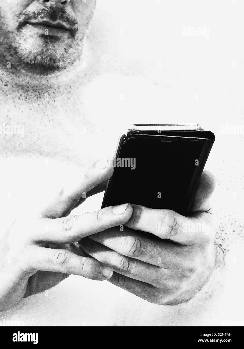 Unshaven man using smartphone Stock Photo