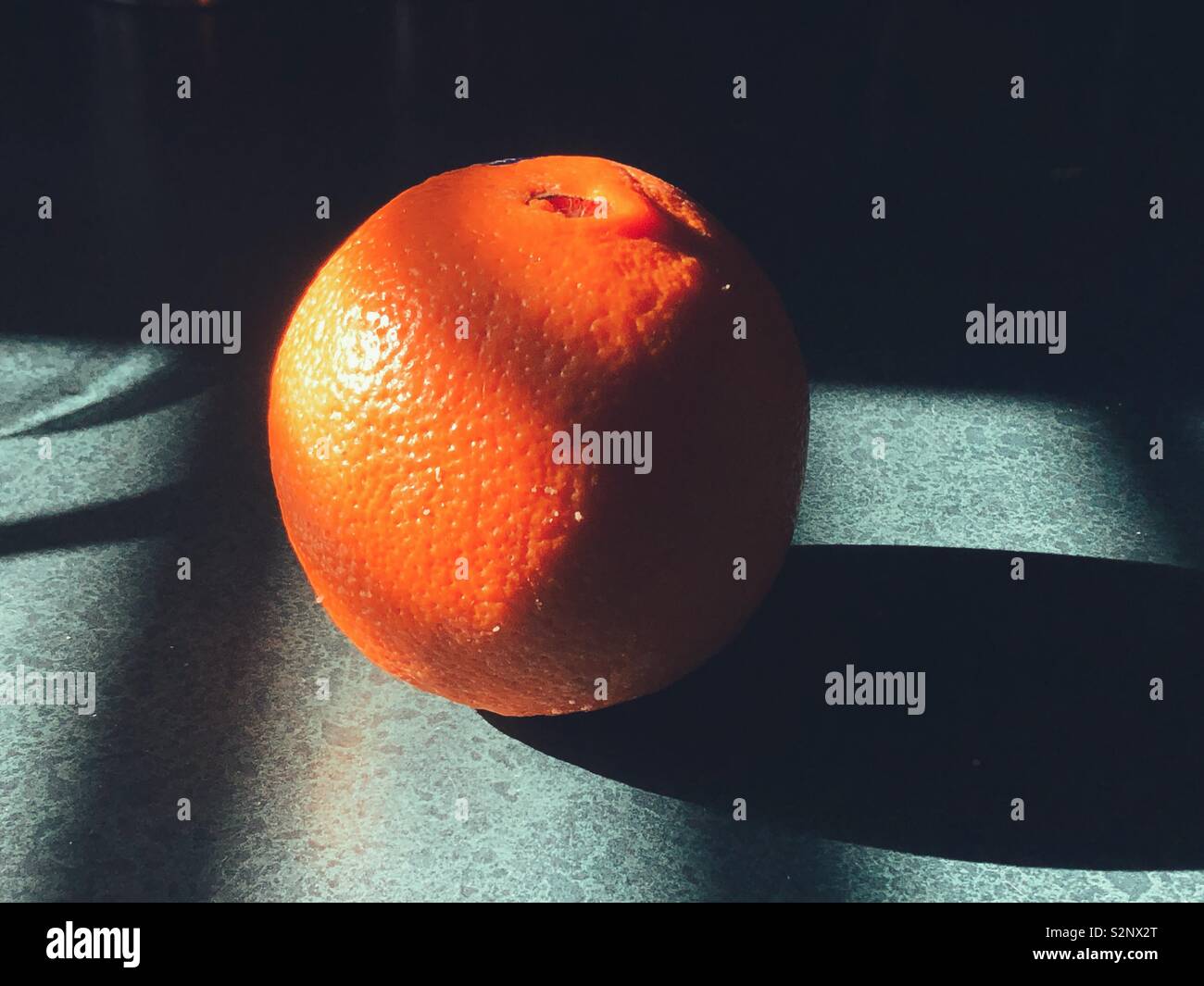 Fresh orange on green kitchen counter surface in the sunlight - Smartphone Captured Stock Image