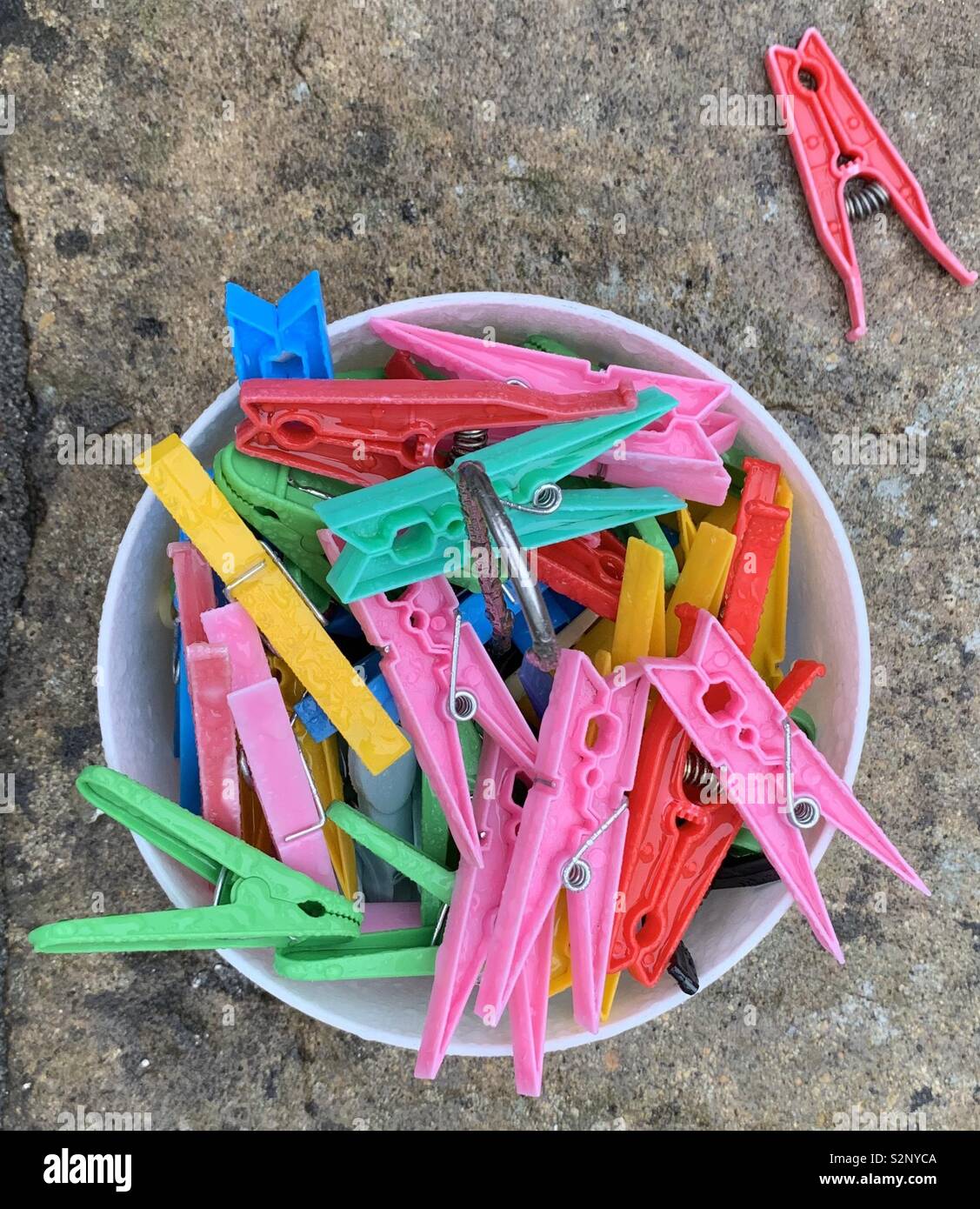 Colourful plastic clothes pegs on paving slab Stock Photo
