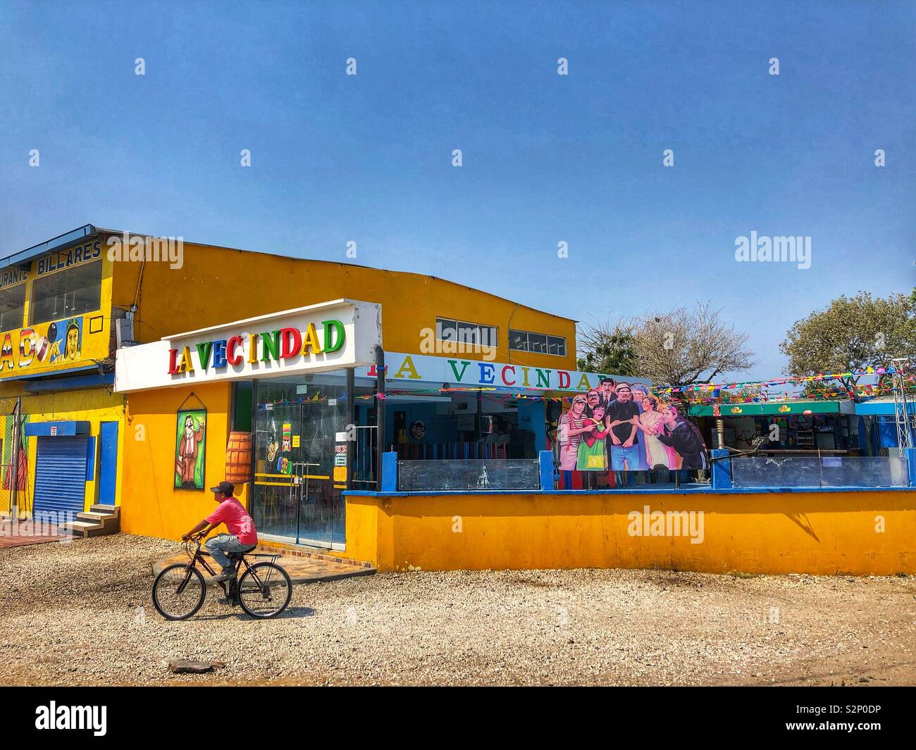 A man cycles by a colourful building in Santa Marta, Colombia. - Smartphone Captured Stock Image