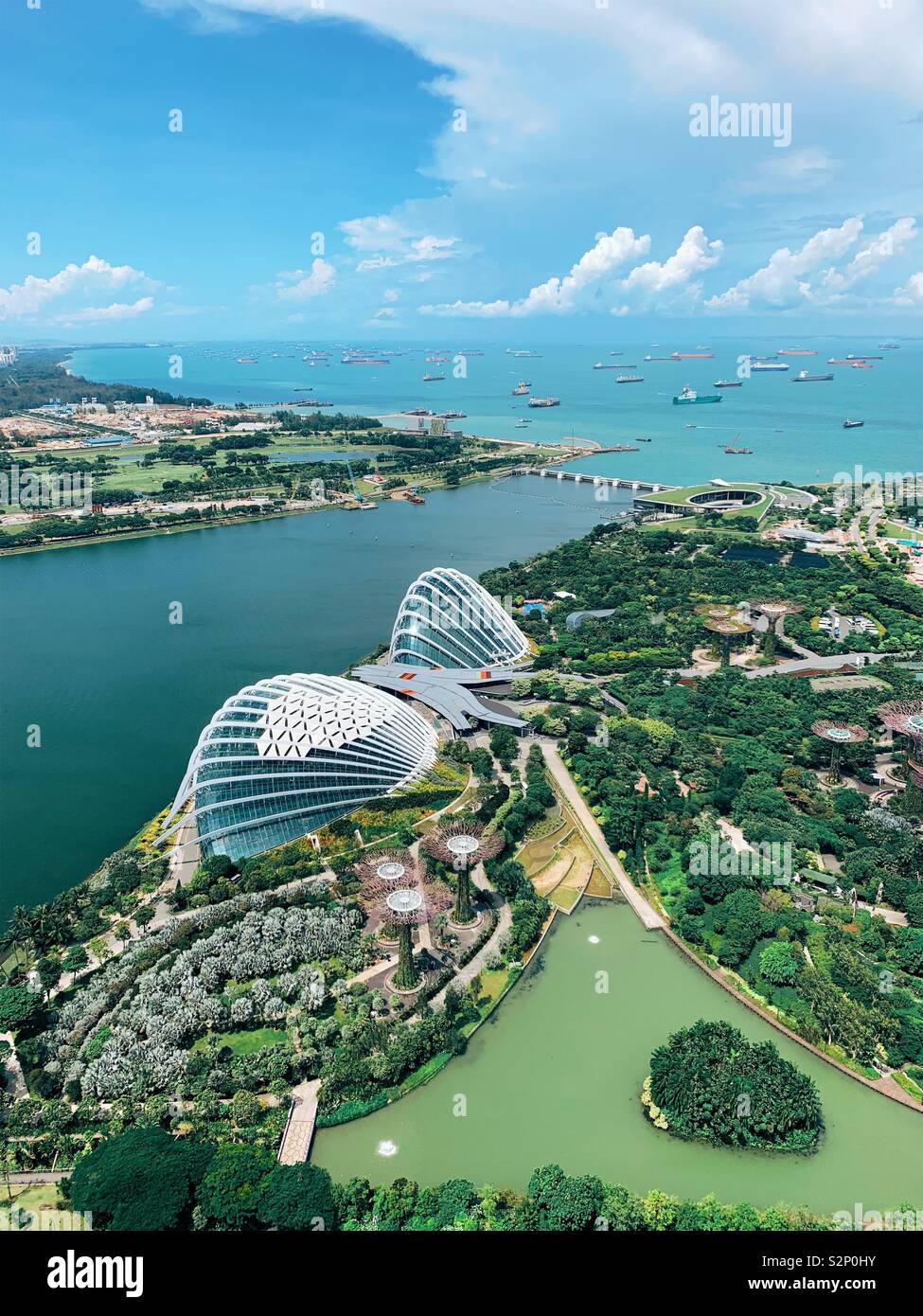 Singapore. View from 57th floor of marina bay sands showing Gardens by the Bay, Super Trees, Flower Dome, Cloud Forest and ships in harbour - Smartphone Captured Stock Image