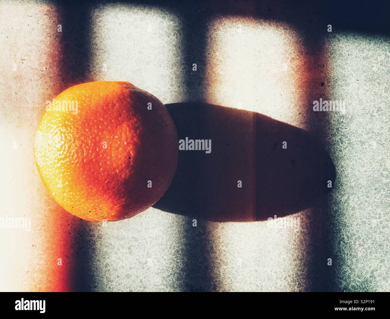Orange in sunlight with shadows from window blinds - Smartphone Captured Stock Image