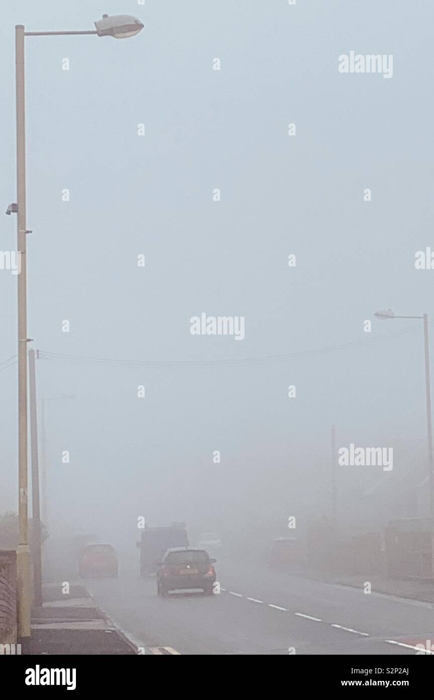 Cars travelling uphill on in foggy day Stock Photo