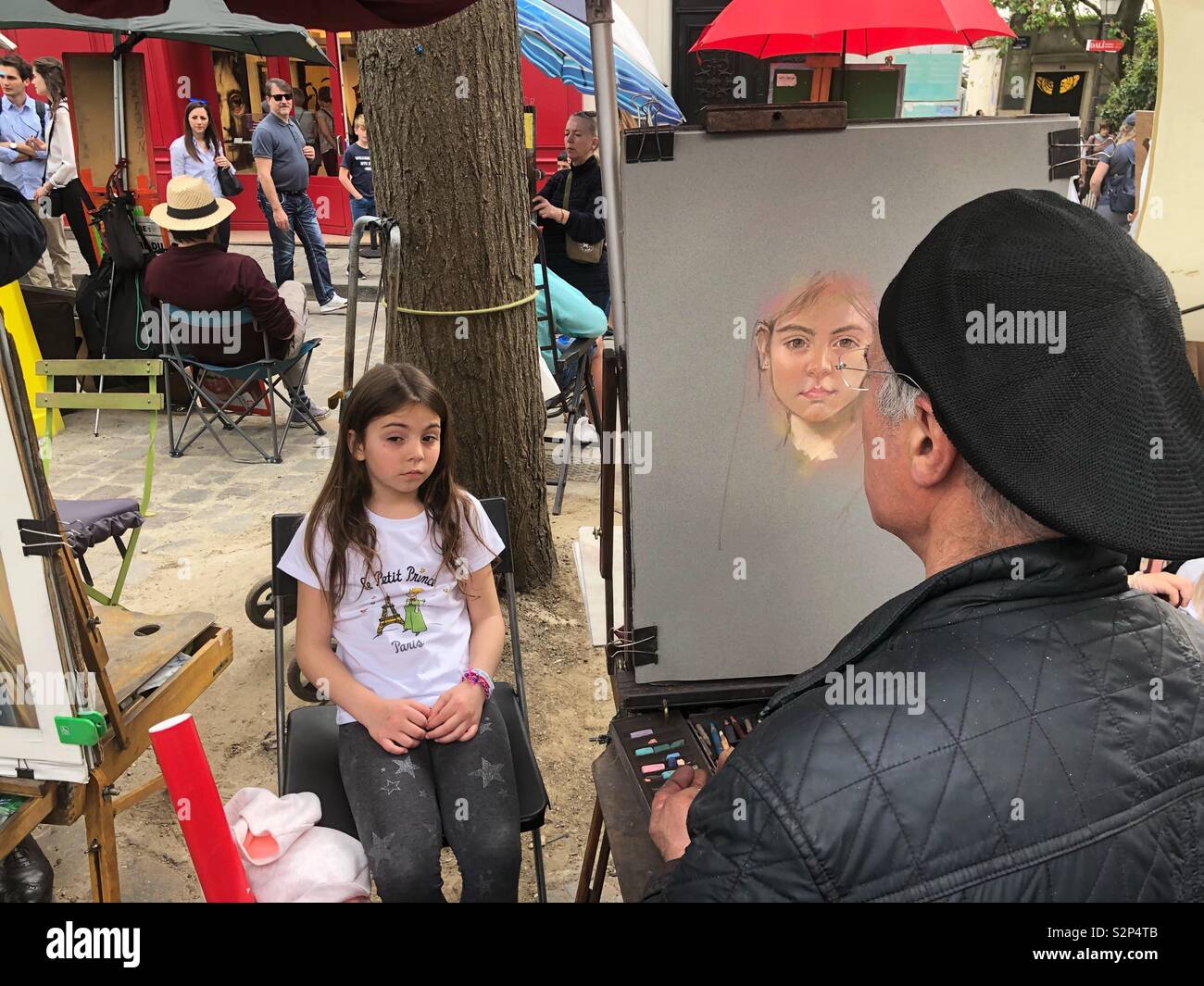 Portrait Artist drawing a beautiful girl in Art square - Montmartre Paris - France - Smartphone Captured Stock Image