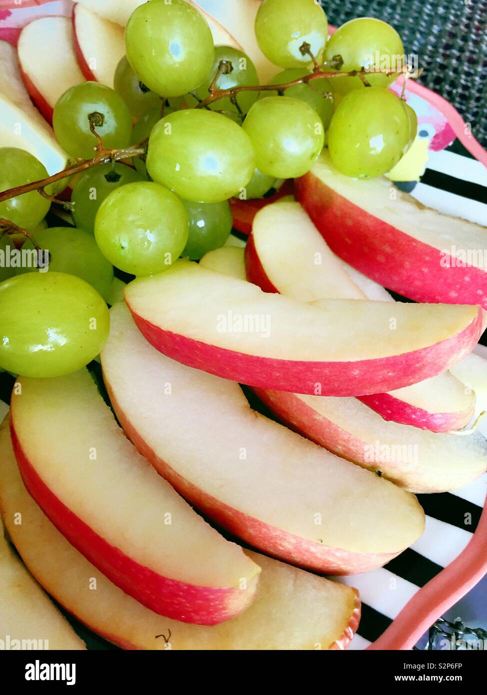 Flat lay close up of a plate of grapes and sliced apples. - Smartphone Captured Stock Image