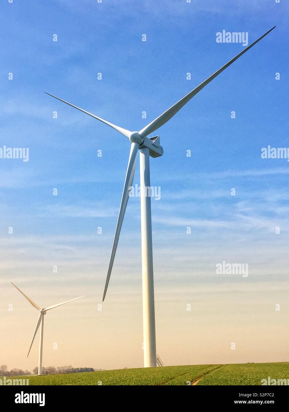 A tall wind power wind mill turbine generating clean electricity in a power or energy generation image with blue sky - Smartphone Captured Stock Image