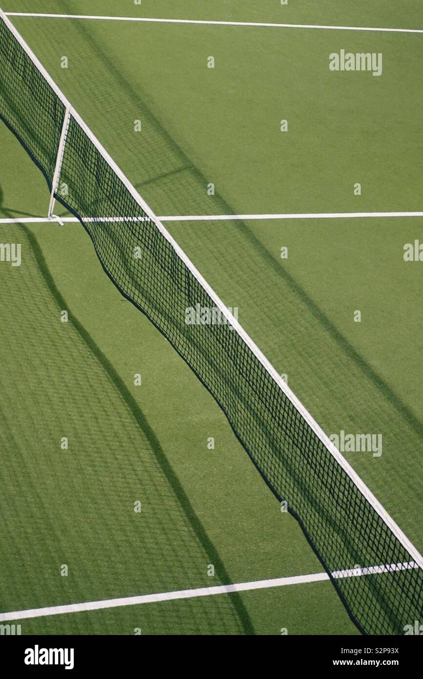 Tennis net. Green Matchfield, some white lines. Minimalistic scenery. Stock Photo