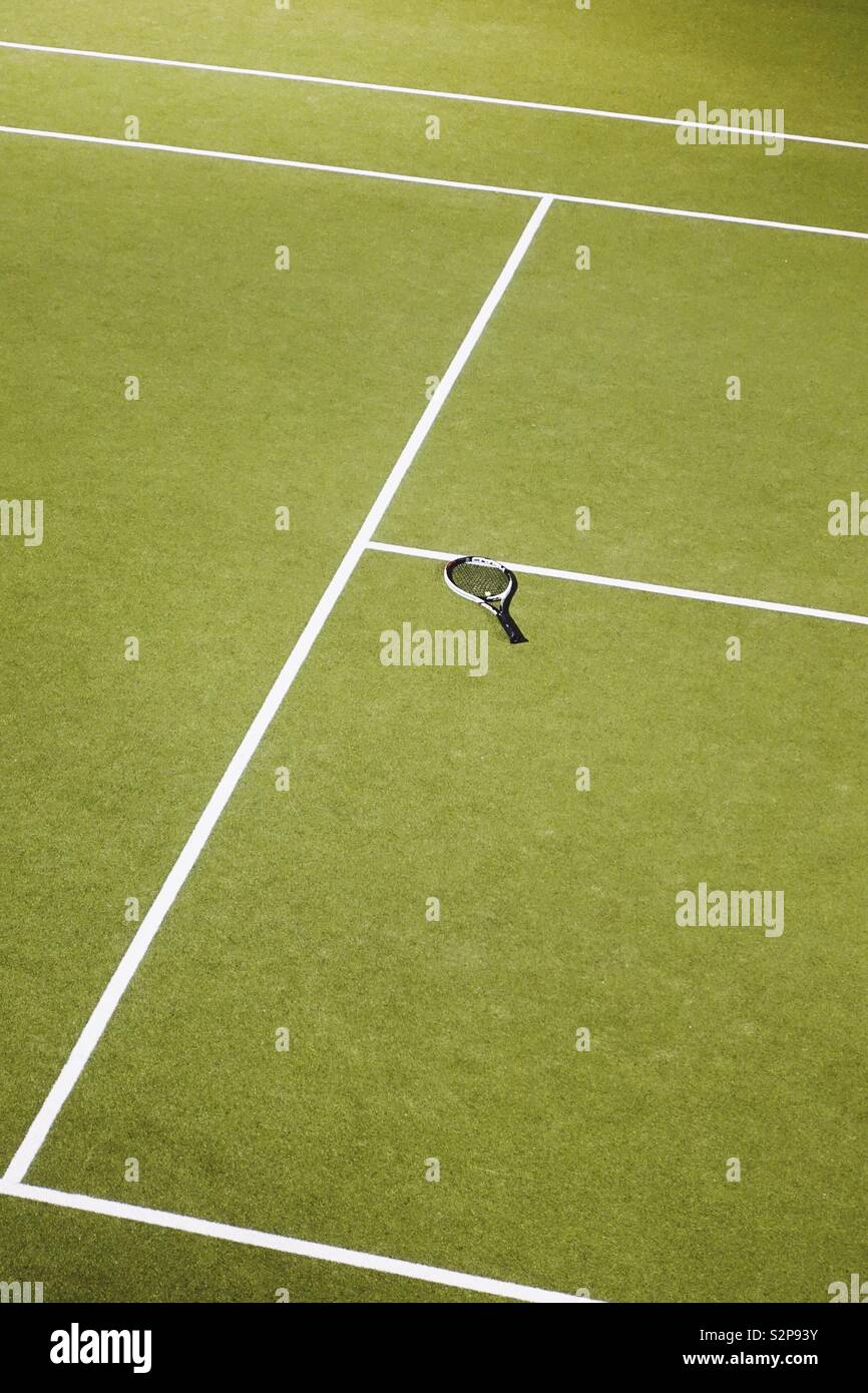 Lost racquet on an empty green tennis court Stock Photo