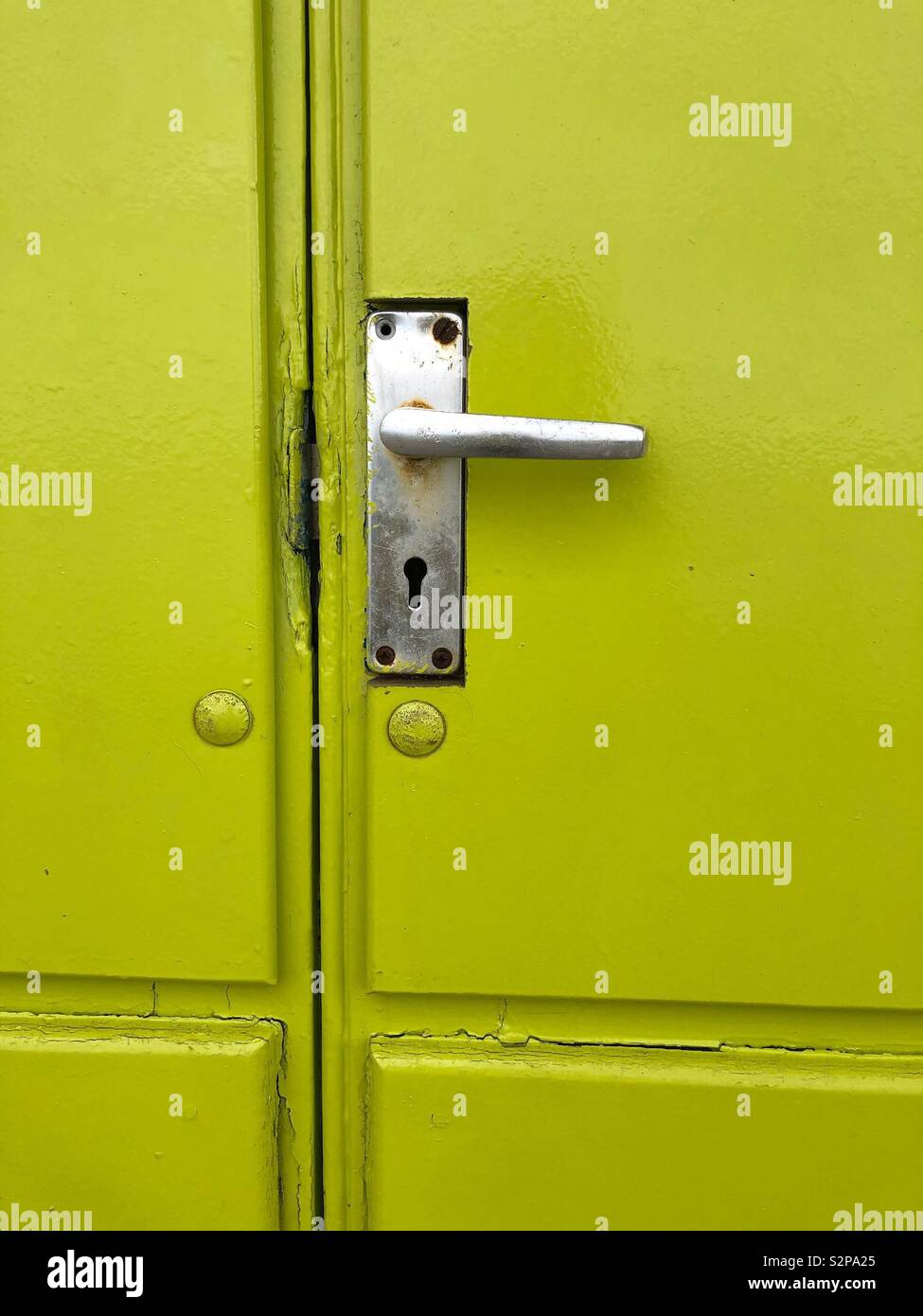 Abstract formed by a lime green painted door with handle and keyhole Stock Photo