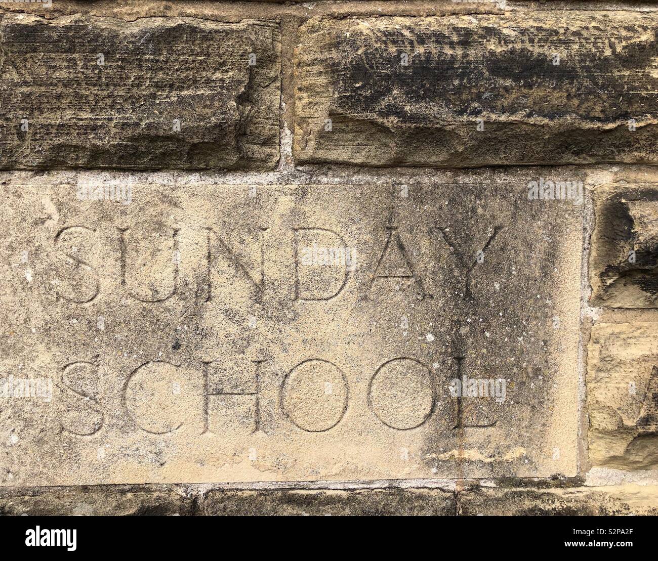 Carved stone embedded in the wall of a Methodist church  - Sunday School - Smartphone Captured Stock Image
